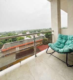 A balcony with a teal chair, a metal railing, and a view of buildings and greenery. - Cozy view of the Harbour (Kingston)