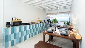 A modern kitchen with a blue and white checkered backsplash, a wooden dining table set for four, and a view of the sea through large windows. - Wander at Bayside 19 | Upstairs Sea-View King Room (sleeps up to 4) (Hua Hin)