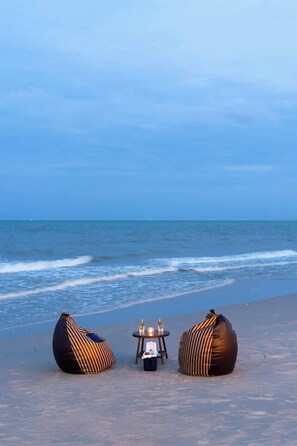 Uma praia com dois sacos de feijão e uma pequena mesa com garrafas.