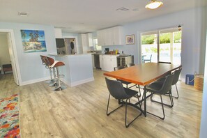 Eine moderne Küche mit weißen Schränken, einem Holztisch und schwarzen Stühlen.