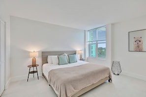 Ein Schlafzimmer mit einem Bett, Nachttischlampen, einem Fenster und einem an der Wand hängenden Bild.