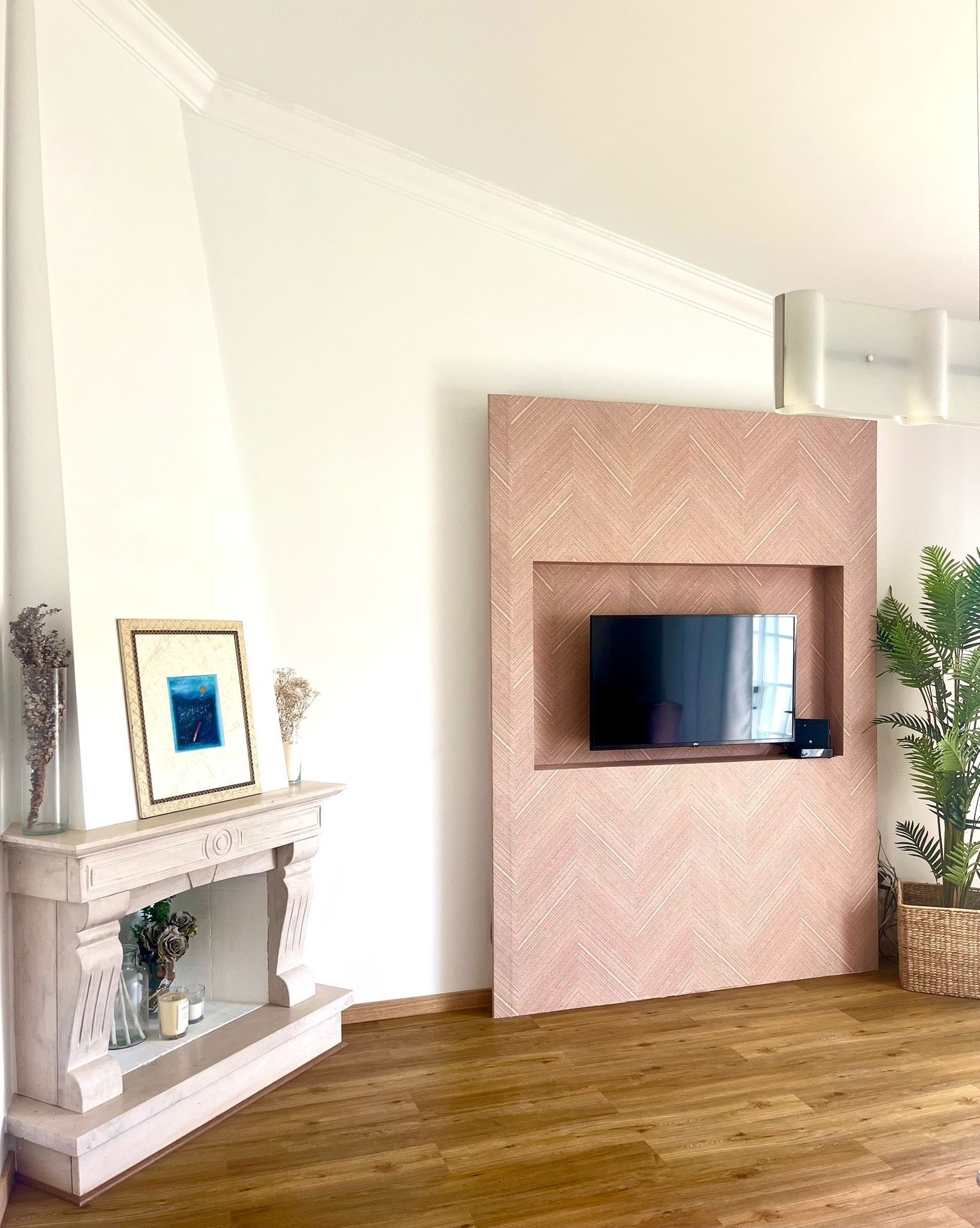 Un salon avec une cheminée, un téléviseur fixé au mur et une plante en pot.