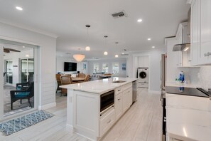 A modern kitchen with white cabinetry, a large island, and a built-in oven. - Shell Yeah! Waterfront House with Private Pool in Palm Acres (Fort Myers)