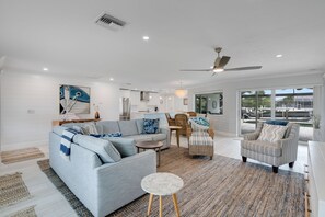 A modern living room with a sofa, armchairs, a coffee table, and a dining area. - Shell Yeah! Waterfront House with Private Pool in Palm Acres (Fort Myers)