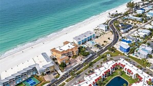 An aerial view of a coastal resort with beachfront properties, a road, and a swimming pool. - Island Breeze Escape (Bradenton Beach)