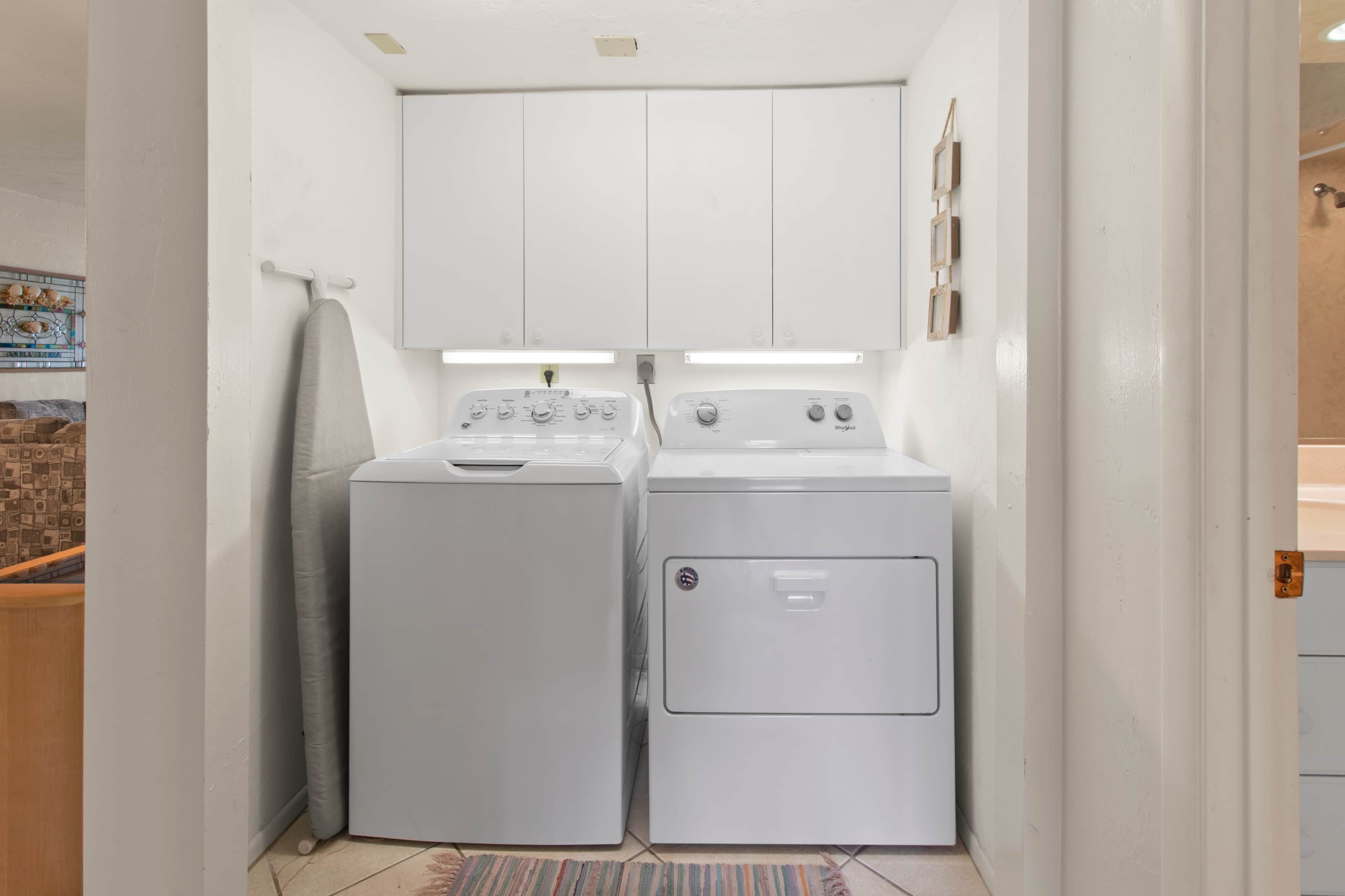 A laundry room with two stacked washers and dryers, a hanging iron, and a tiled floor.