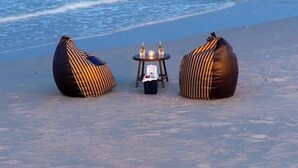 Una spiaggia con due sacchi di fagioli e un tavolino con delle bottiglie.