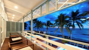 Un balcone con pavimento in legno, una piscina e vista sull'oceano al crepuscolo.