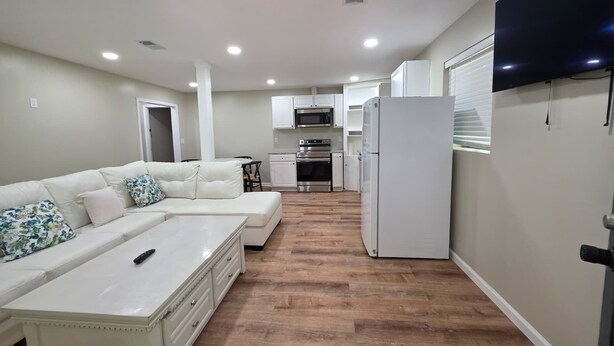 Un appartement moderne comprenant un salon, une kitchenette et un téléviseur fixé au mur.