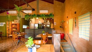 A wooden interior with a bar area, dining tables, and potted plants.
