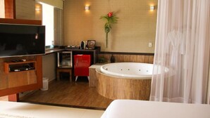 Une salle de bain moderne avec une baignoire, un téléviseur, un meuble rouge et un miroir.