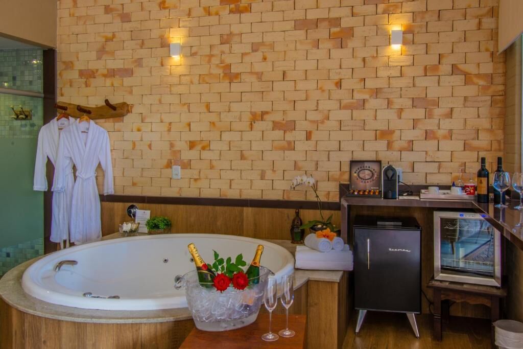 Bagno con parete in mattoni, vasca, minibar e piccolo frigorifero.