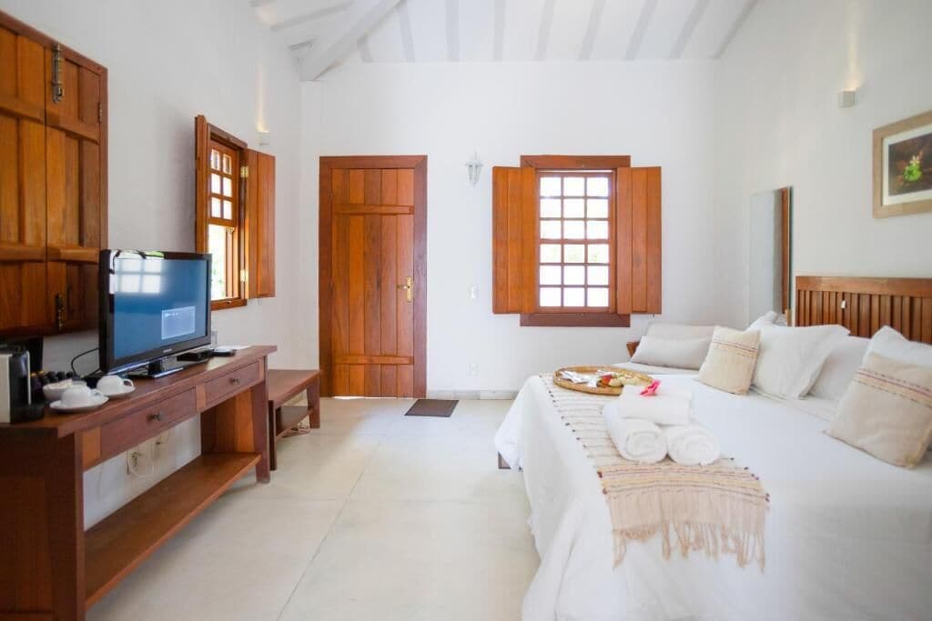 Una habitación con cama, televisión, armarios de madera y ventana.