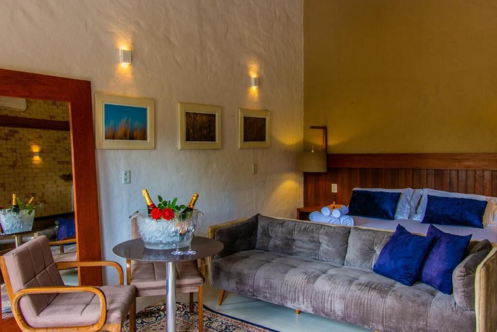 Una habitación acogedora con un sofá gris, una mesita redonda con una bebida y un cabecero de madera.