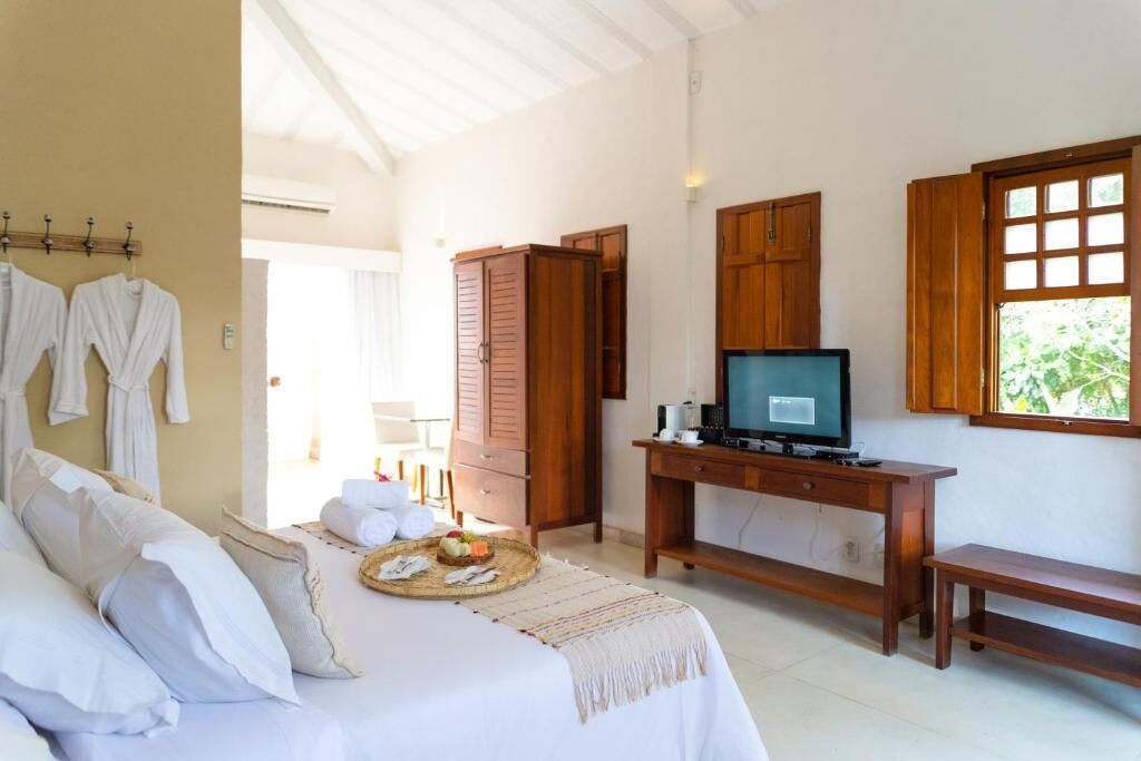 A bedroom with a bed, a desk with a television, wooden cabinets, and a window.