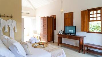A bedroom with a bed, a desk with a television, wooden cabinets, and a window.