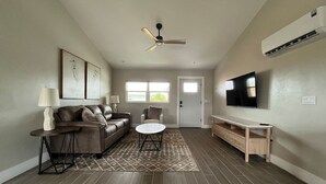 Ein Wohnzimmer mit Sofa, Couchtisch, Fernseher und Deckenventilator.