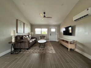 Ein Wohnzimmer mit Sofa, Couchtisch, Fernseher und Deckenventilator.