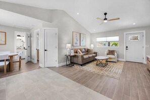 A spacious living area with a sofa, armchairs, a coffee table, and a dining table. - The Wells at Coconut Cove (Fort Myers Beach)