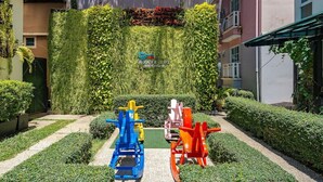 Un cortile con parete verde, attrezzature per l'esercizio fisico e siepi curate.