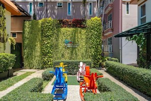 Ein Innenhof mit grüner Wand, Fitnessgeräten und ordentlich geschnittenen Hecken.