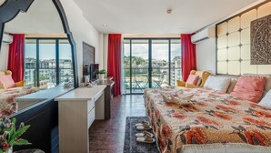 Una camera d'albergo moderna con balcone, una scrivania, un letto e un'ampia finestra.