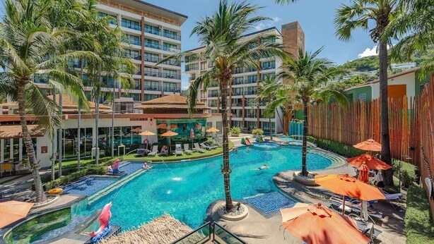 Un hotel con piscina circondata da palme e lettini.