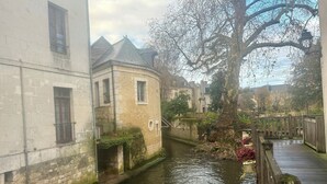 Um canal estreito com edifícios de um lado e uma ponte de madeira.