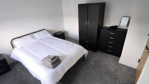 A bedroom with a bed, a wardrobe, a nightstand, and a small table. - Room-bright Double Room in Chelmsford Ho (Chelmsford)