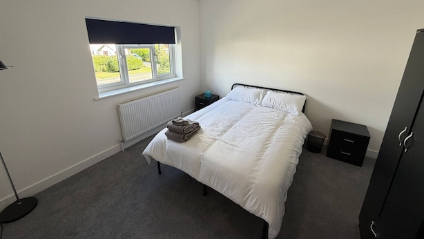 A bedroom with a bed, a radiator, a window, a bedside table, and a wardrobe. - Room-bright Double Room in Chelmsford Ho (Chelmsford)