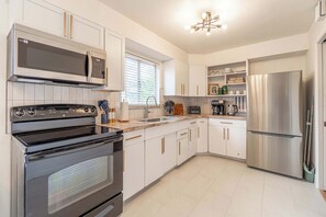 A modern kitchen with stainless steel appliances, white cabinetry, and a built-in oven. - 4BR Home w/ Hot Tub, Grill, Foosball & Cornhole (Reno)