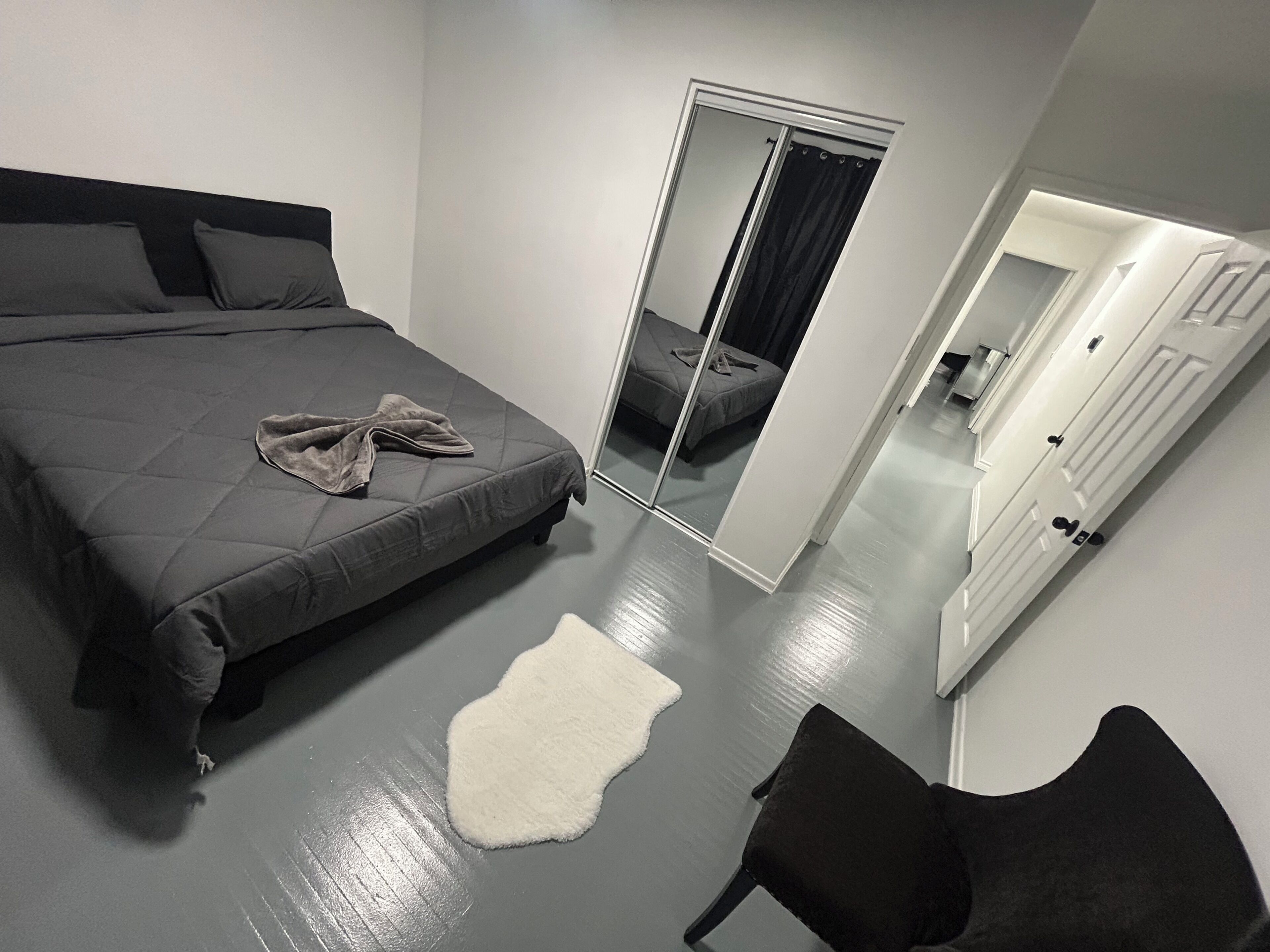 Une chambre à coucher avec un lit, un miroir, une chaise et une porte.