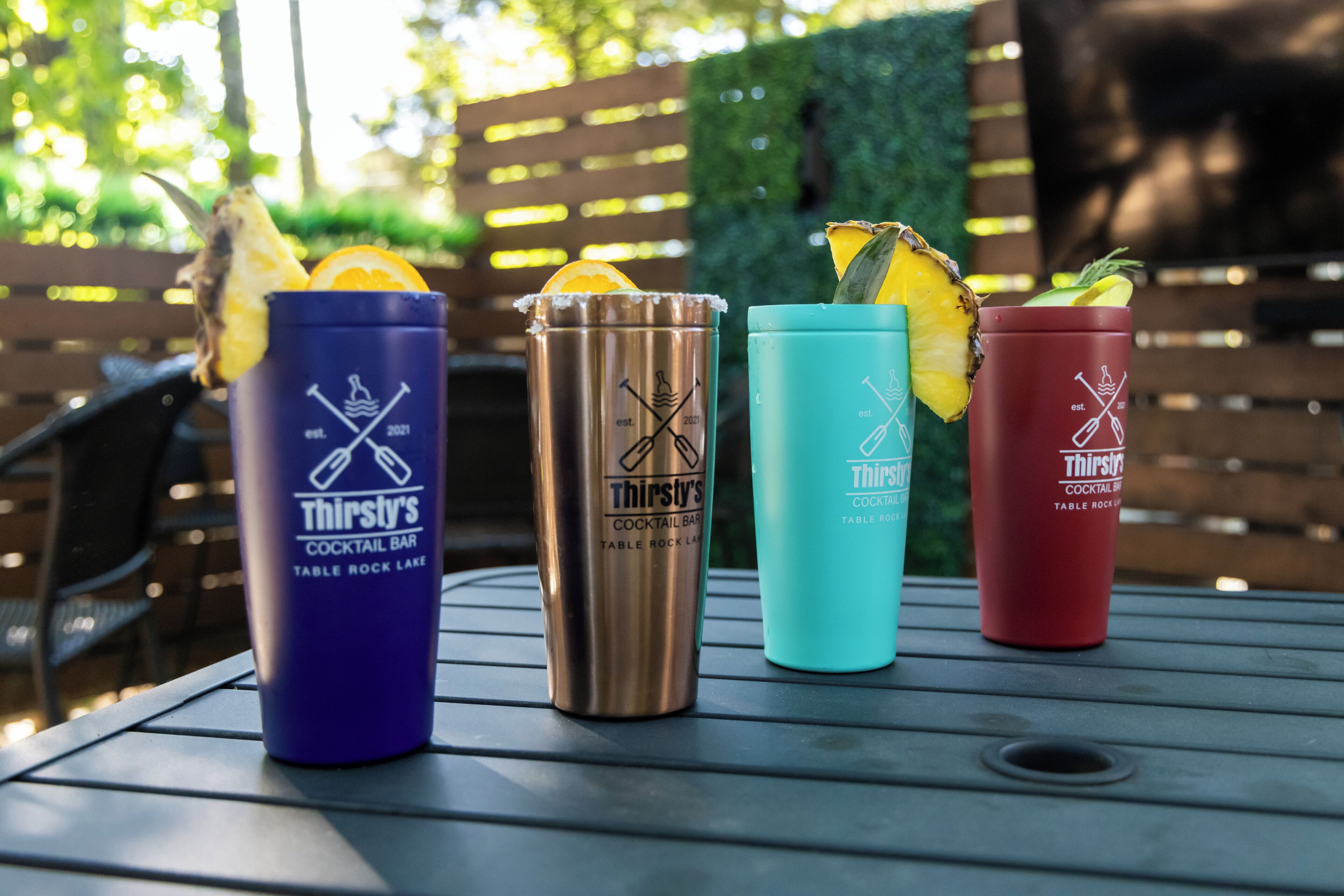 Cuatro vasos de bar estilo 'Four Thirsty's' sobre una mesa al aire libre.