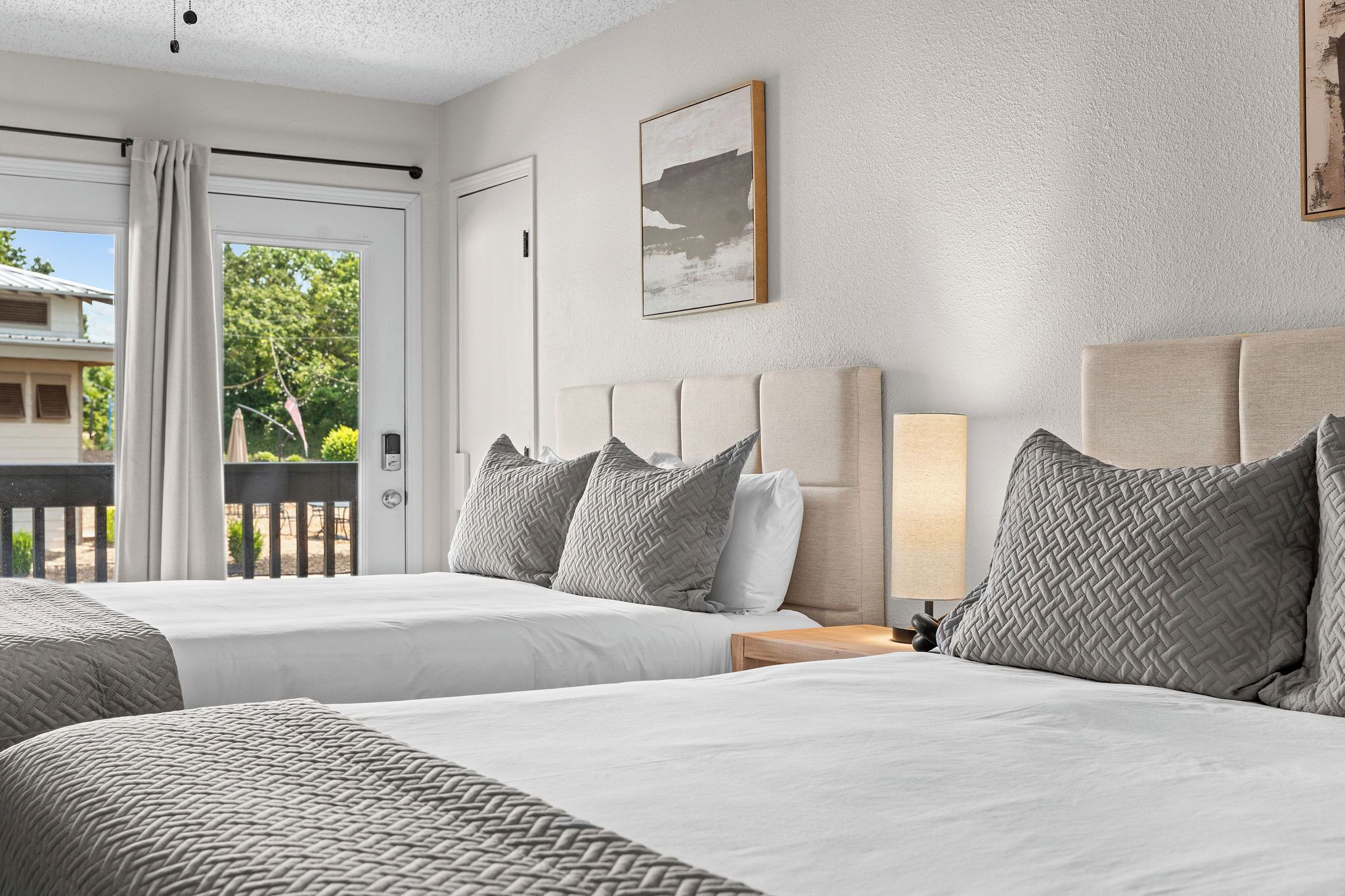 Una habitación de hotel con dos camas, vistas al exterior y un cuadro en la pared.