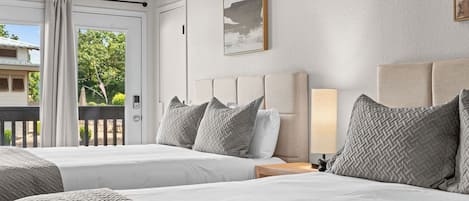 A hotel room with two beds, a view of the outdoors, and a painting on the wall.