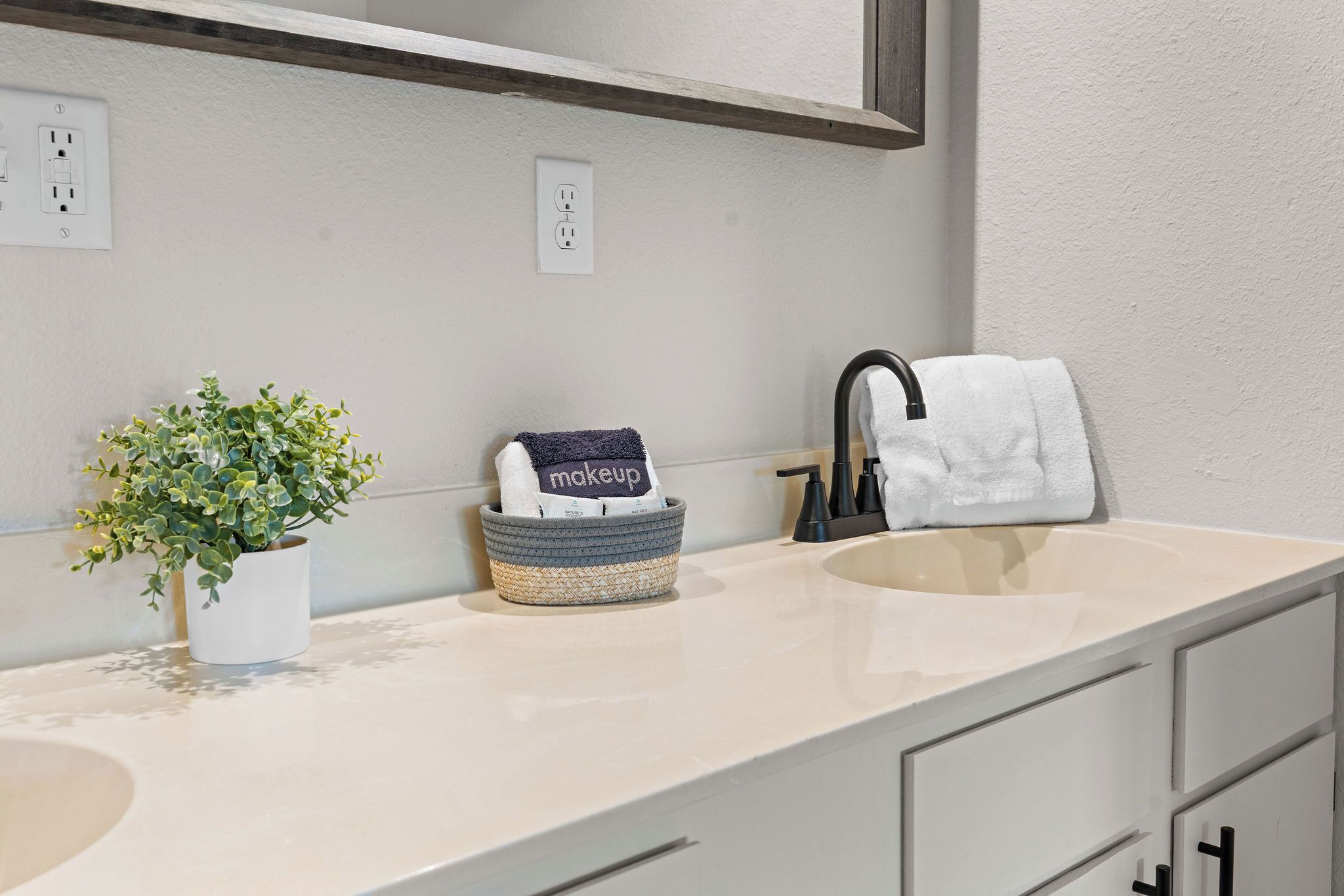 A bathroom with a sink, a towel rack, a potted plant, and a basket with a towel.