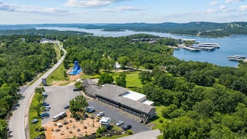 A large building with a parking lot, a water slide, and a view of a lake with boats.