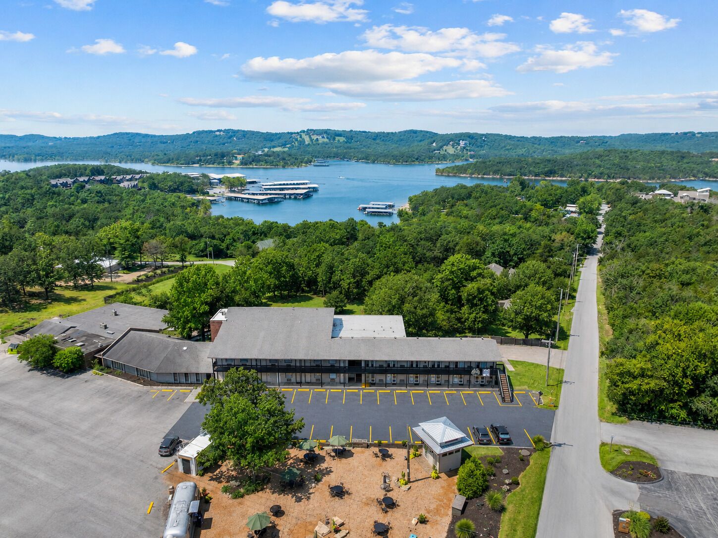 Un hotel con estacionamiento, asientos al aire libre y vistas a un lago con barcos.