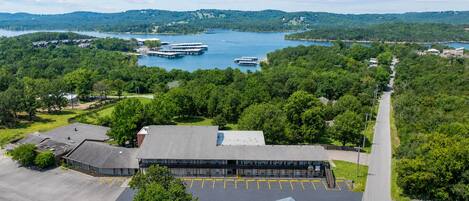 Un hotel con estacionamiento, asientos al aire libre y vistas a un lago con barcos.