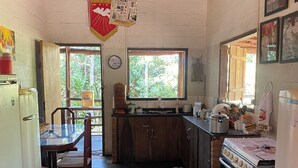 Uma cozinha compacta com área de refeições, teto de madeira e janela com vista para o verde.