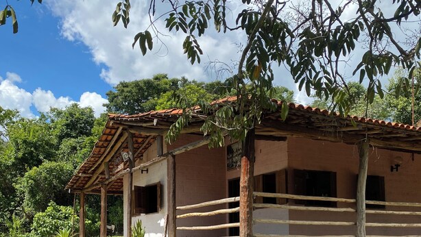 Um edifício rústico com telhado de telhas, parede de pedra e área cercada.