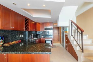 Eine moderne Küche mit dunklen Granit Arbeitsplatten, Holzschränken und einer zentralen Kochinsel.