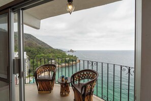 Ein Balkon mit Korbmöbeln und Blick aufs Meer.