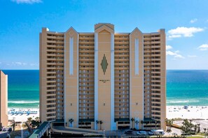A multi-story hotel with a central entrance, balconies, and a beach view. - High-Floor Gulf View & Balcony - Emerald Skies (Panama City Beach)