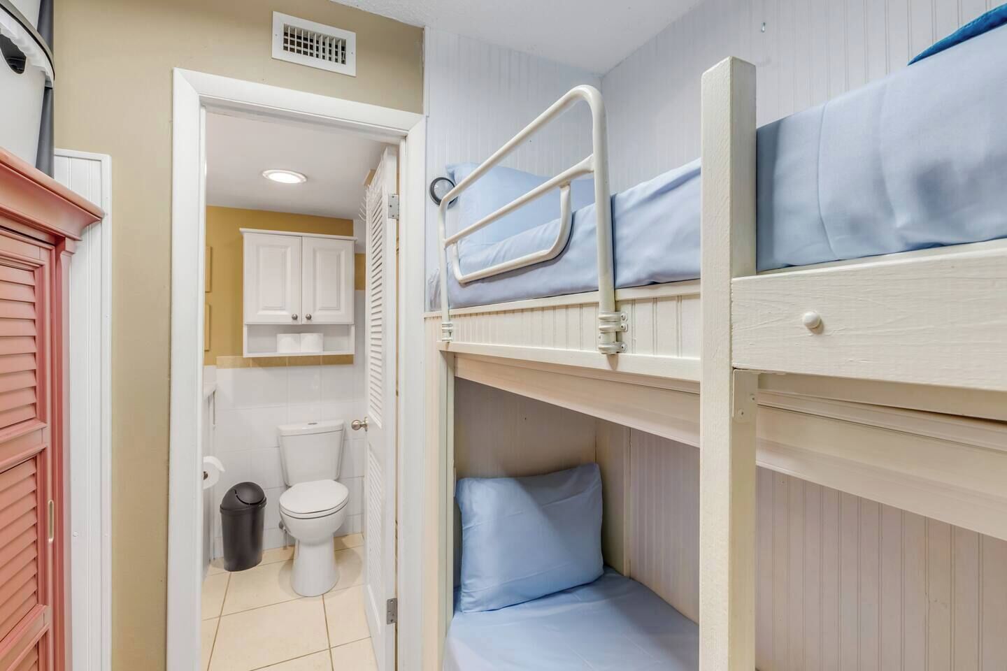 A bunk bed room with a toilet and a small bathroom.
