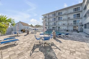 A hotel with a pool area, outdoor seating, and a multi-story building with balconies. - Mariners Cove Condo | Steps to Beach | Pool (New Smyrna Beach)