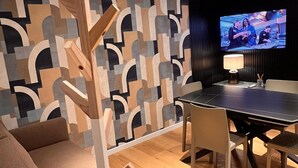 Moderni olohuone, jossa on geometrisesti kuvioitu seinä, ruokapöytä ja televisio.