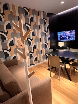 A modern living room with a geometric-patterned wall, a dining table, and a television.