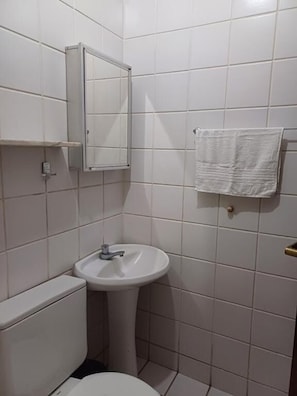 Ein Badezimmer mit einem weißen Waschbecken, einer Toilette, einem Spiegel und einem Handtuch an einem Halter.