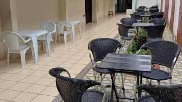 An outdoor patio with tables and chairs, a tiled floor, and a covered area with a railing. - Hotel Merlini  (Belém)